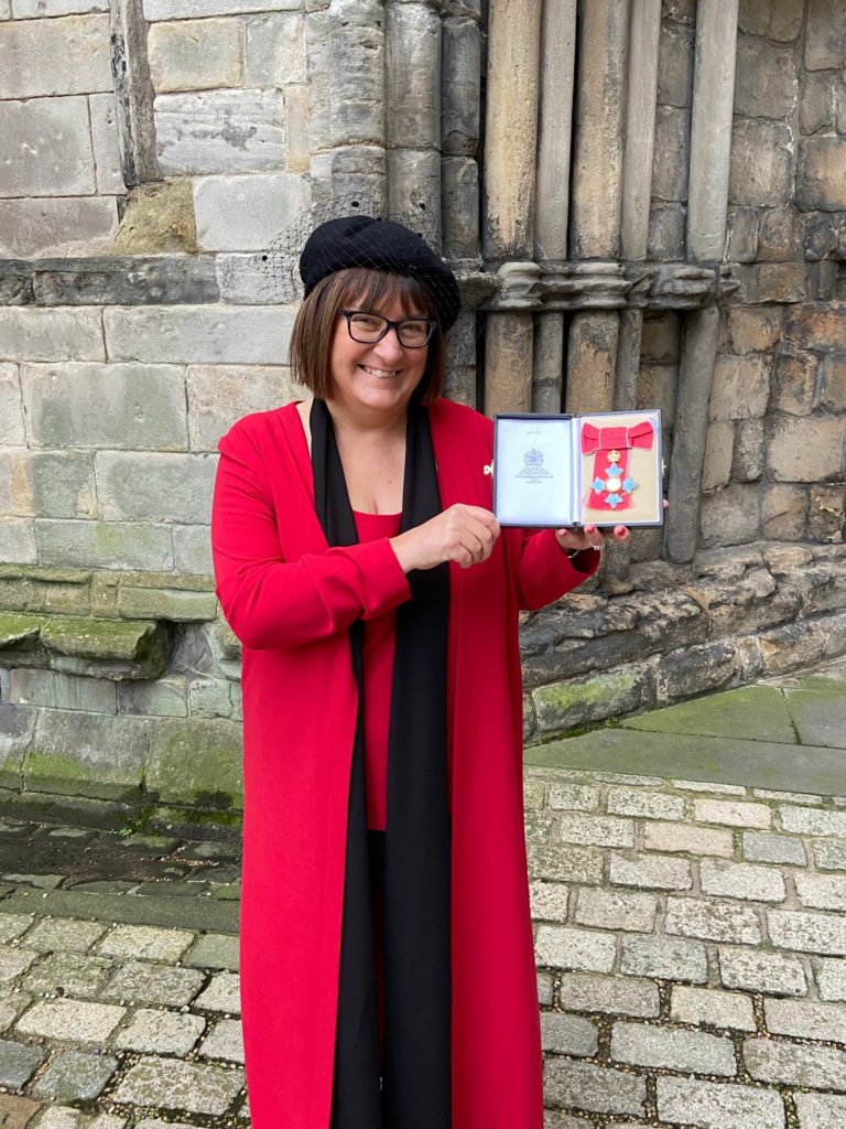 Lady holds up her CBE at Windsor Castle