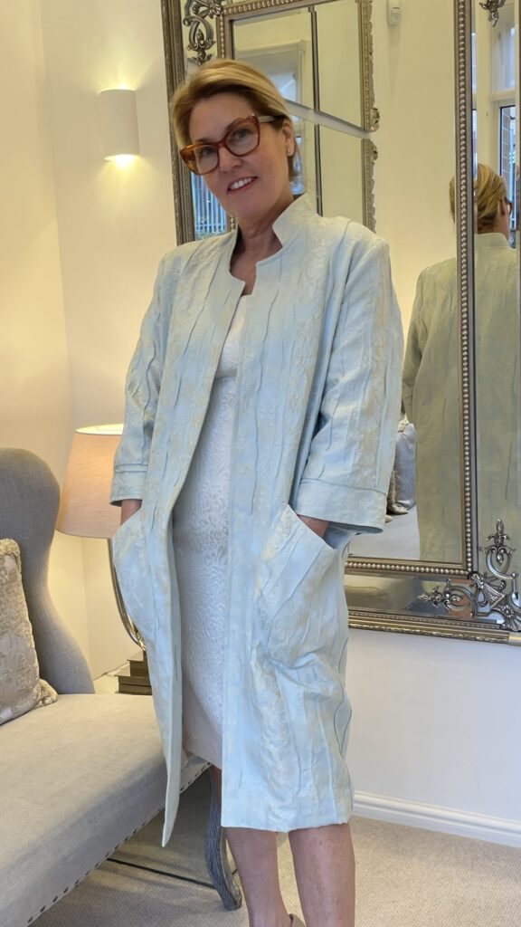 model with hands in pockets wearing a beautiful jacqaurd coat in mint and ivory