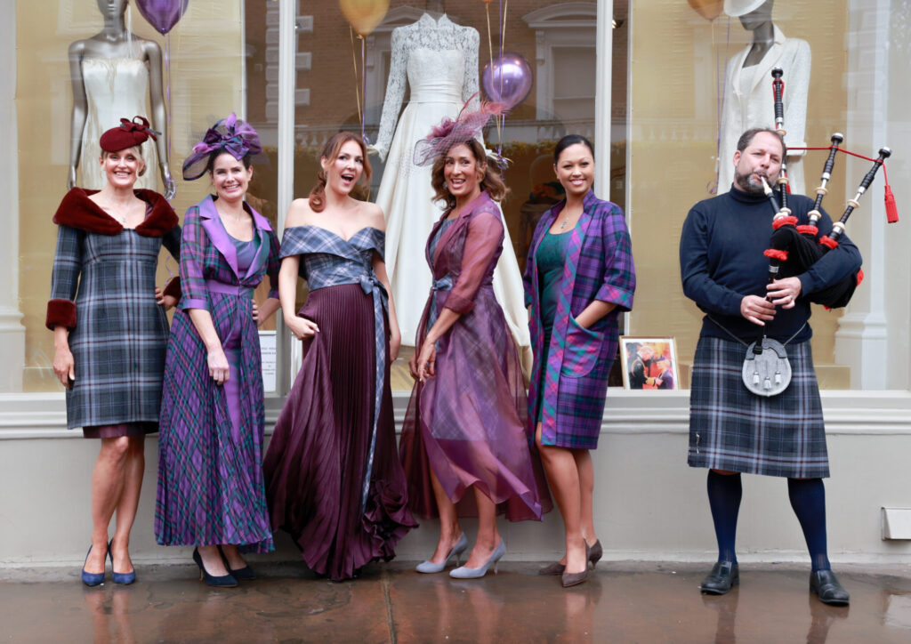 Bagpiper and models dressed in tartan outside shop