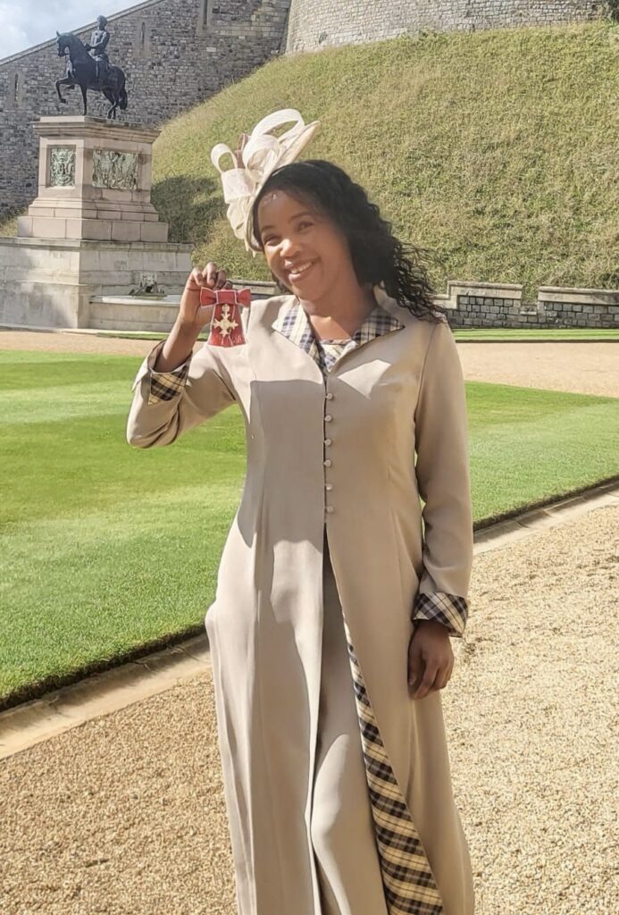 lady holds up MBE medal at Windsor Castle