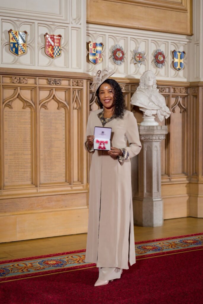 Women holding up MBE medal at Windsor Castle