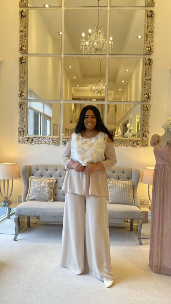 model in trousers standing in front of large mirror