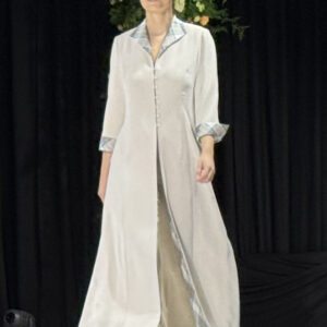 Model on catwalk wearing long silk coat with tartan collar and cuffs coordinaling