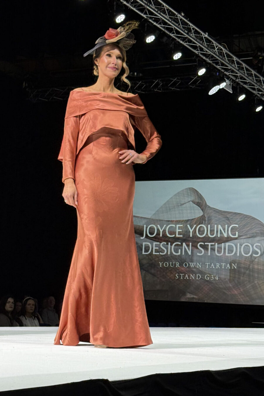 model posing on catwalk wearing terracotta satin dress and jacket