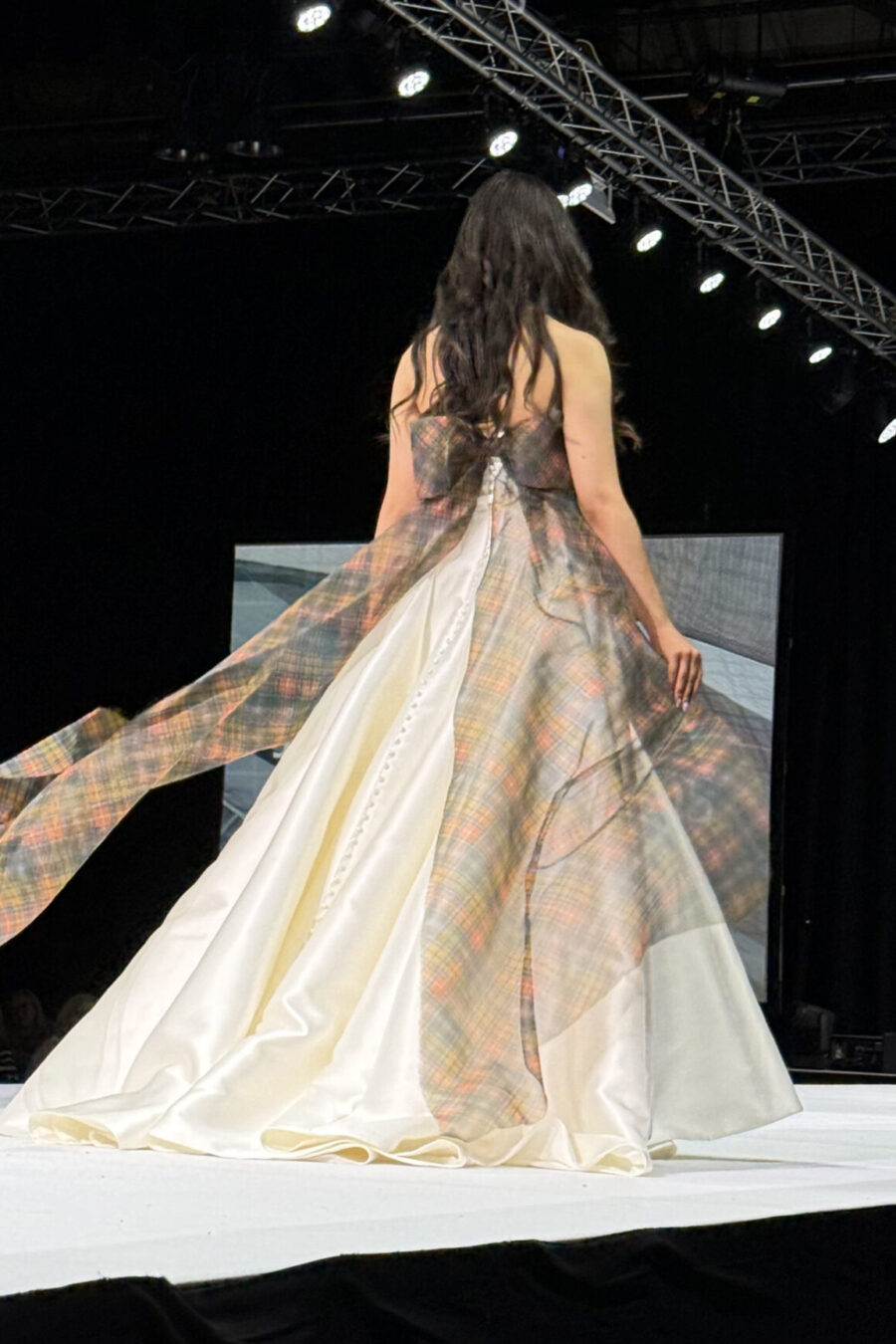 Model walking on the catwalk in ivory wedding dress with buchanan tartan organza bow anfd tiers